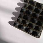 Overhead view of multiple handmade ceramic paintbrush holders in dark blue finish tightly packed in a row.