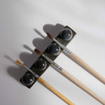 Overhead view of a handmade ceramic paintbrush holder in dark blue finish, holding three paintbrushes.