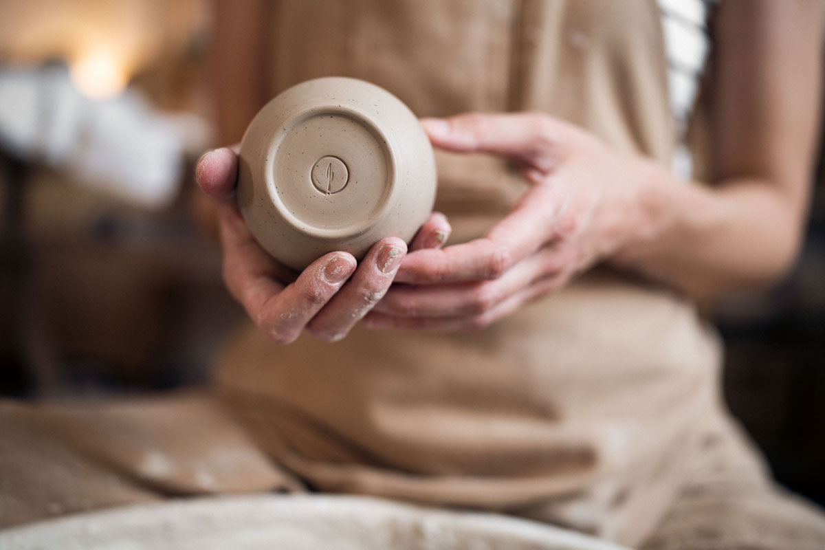 A newly trimmed ceramic cup cradled in hands.