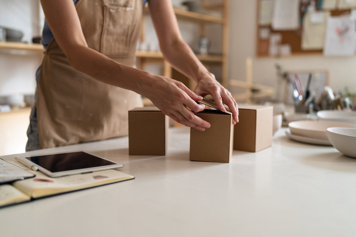 Packaging ceramics into cardboard boxes at the pottery studio.
