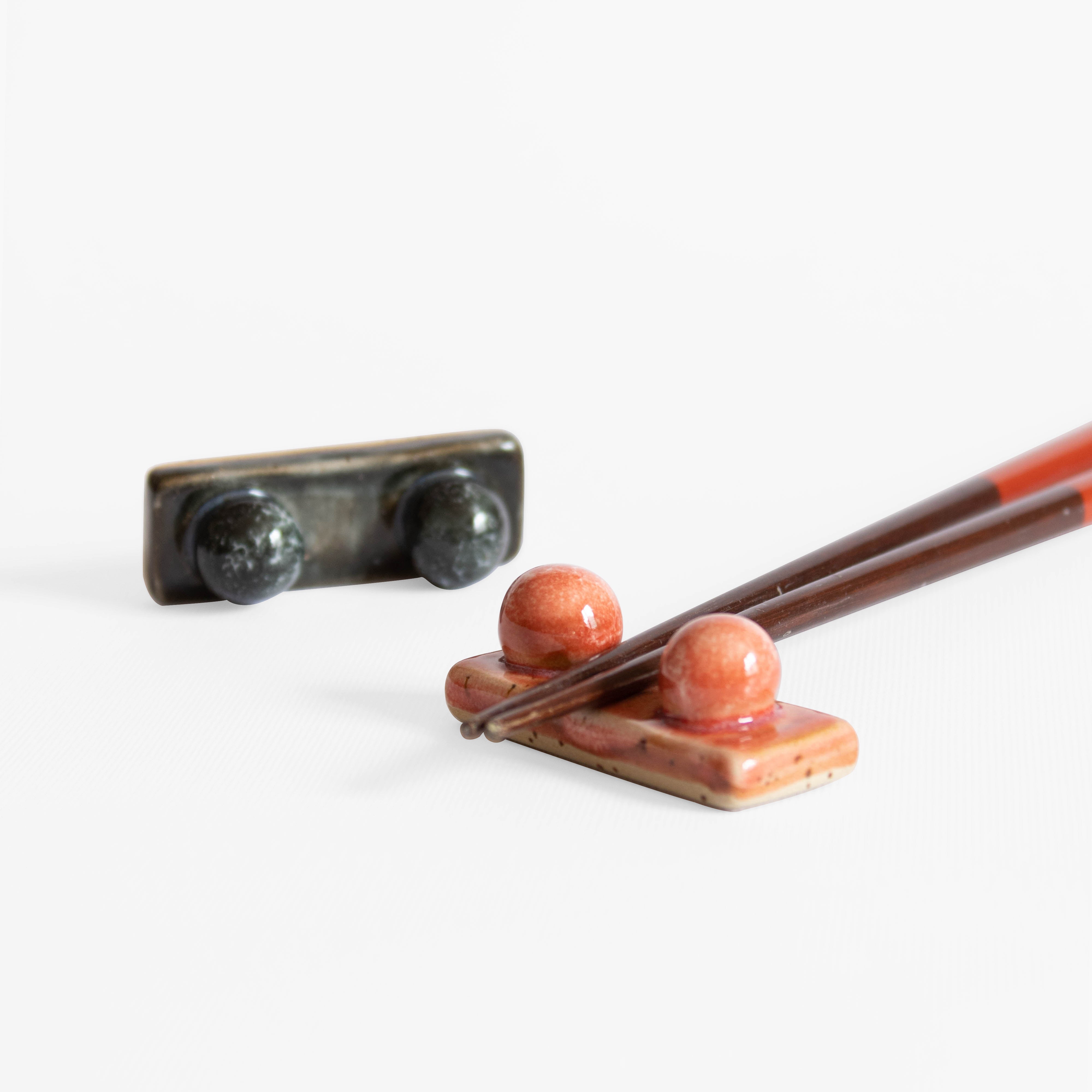 Handcrafted midnight blue and coral red chopstick rest with wooden chopsticks displayed on a white surface.