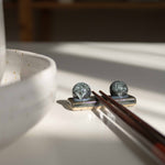 Handcrafted midnight blue chopstick rest with wooden chopsticks, placed next to a speckled white dining set.