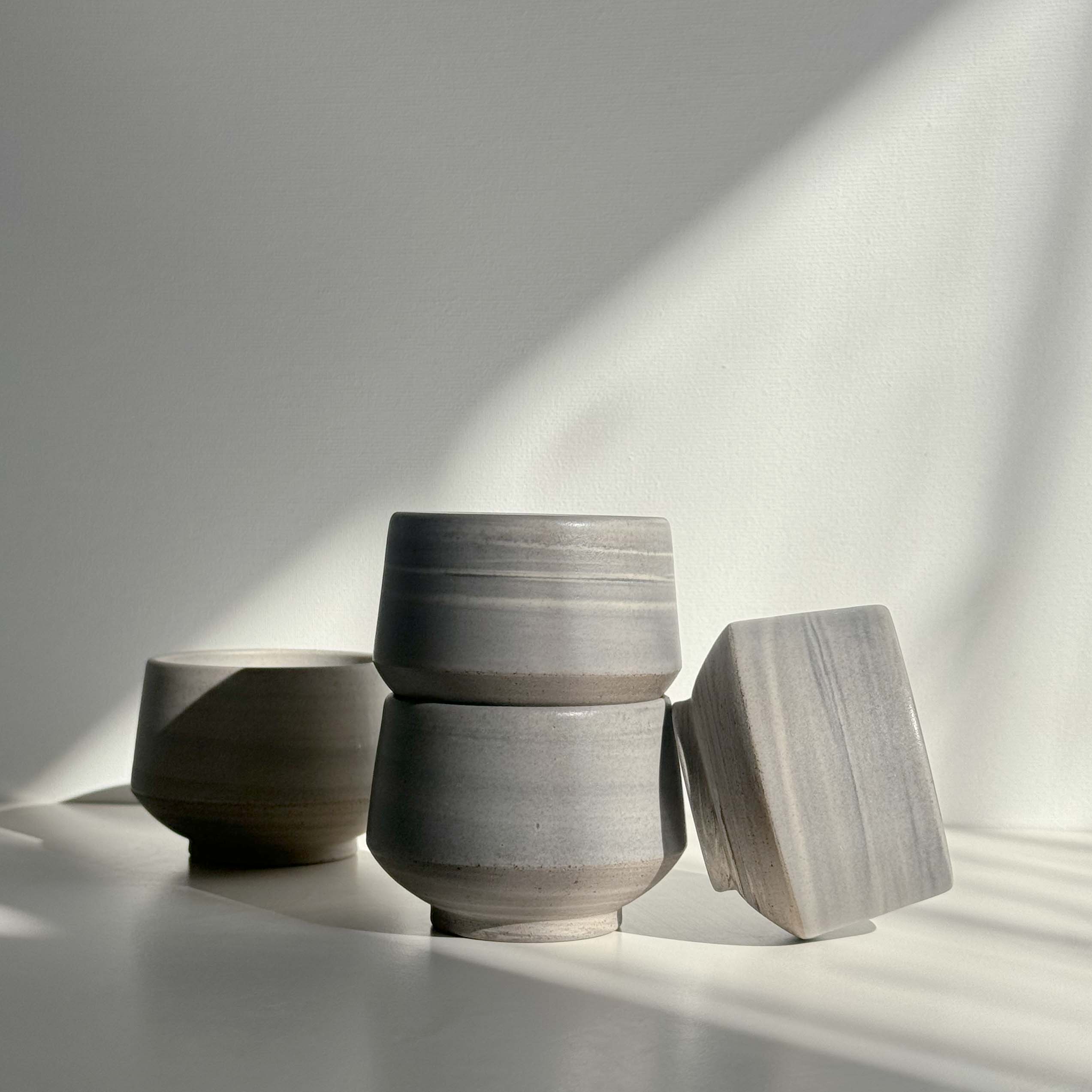 A group of handcrafted cups in natural earthy tones.