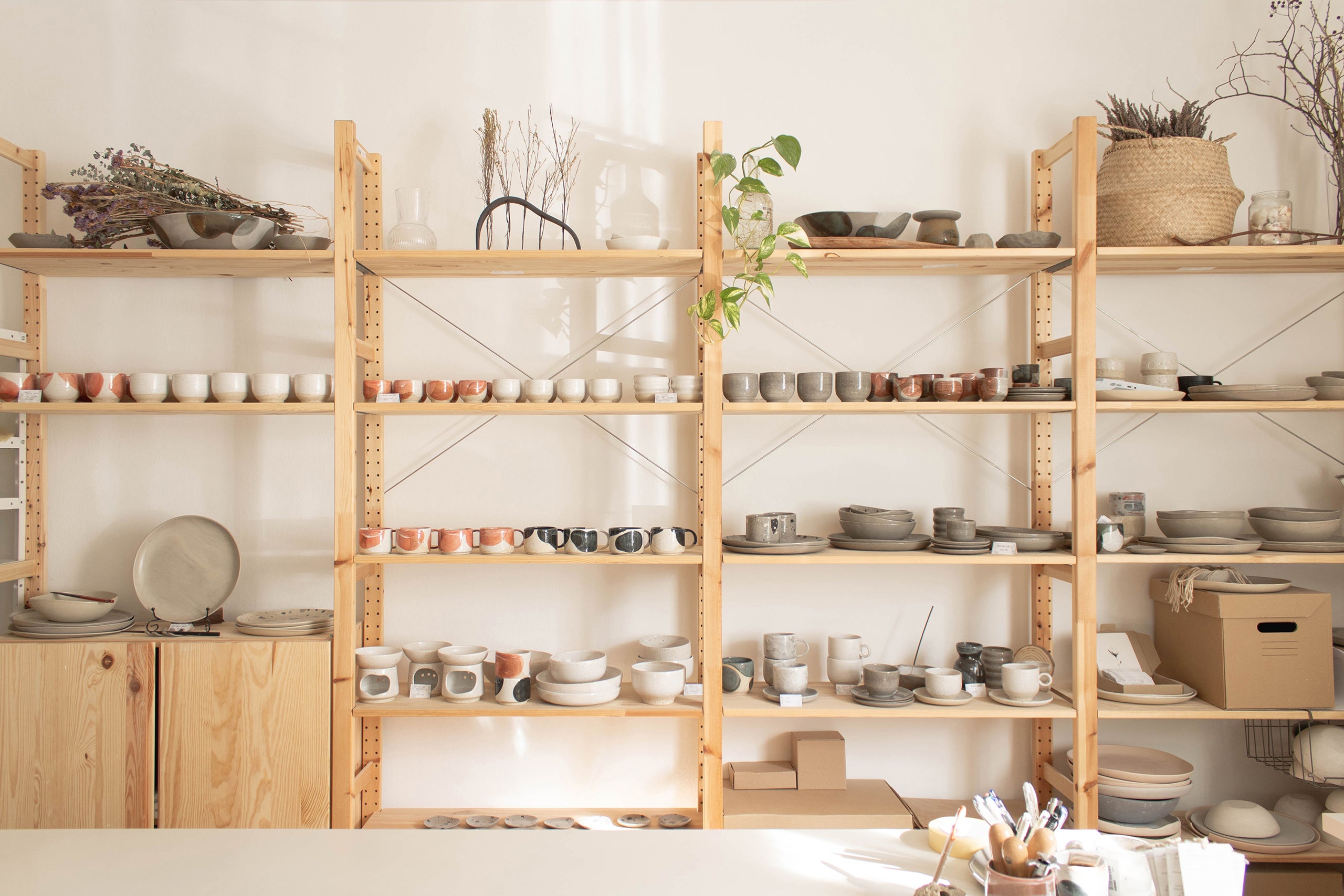 Pottery shelf at Made of Dust studio featuring various handmade ceramic objects.