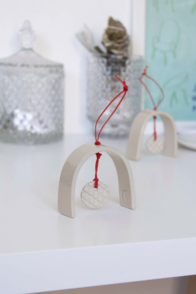 A handmade Christmas ornament shaped like a stylized bell, resting on the tabletop.