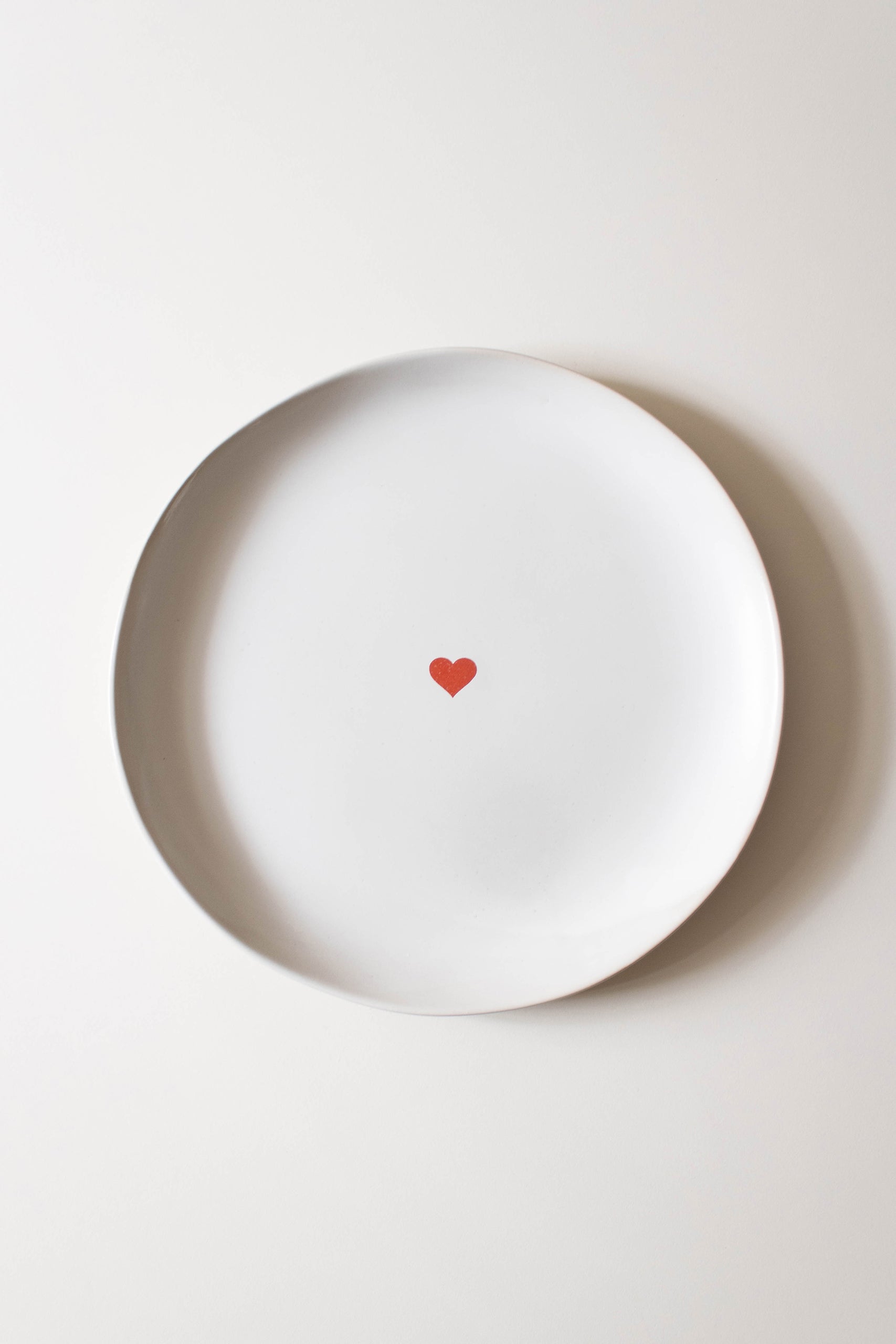 Top-down view of a white lunch plate featuring a small red heart centered on its surface.