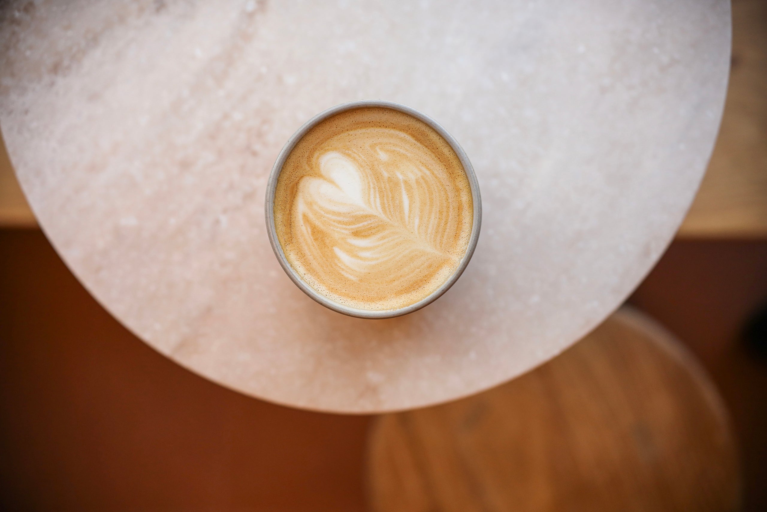 Overhead view of ceramic coffee cup filled with a freshly brewed latte adorned with tulip latte art.