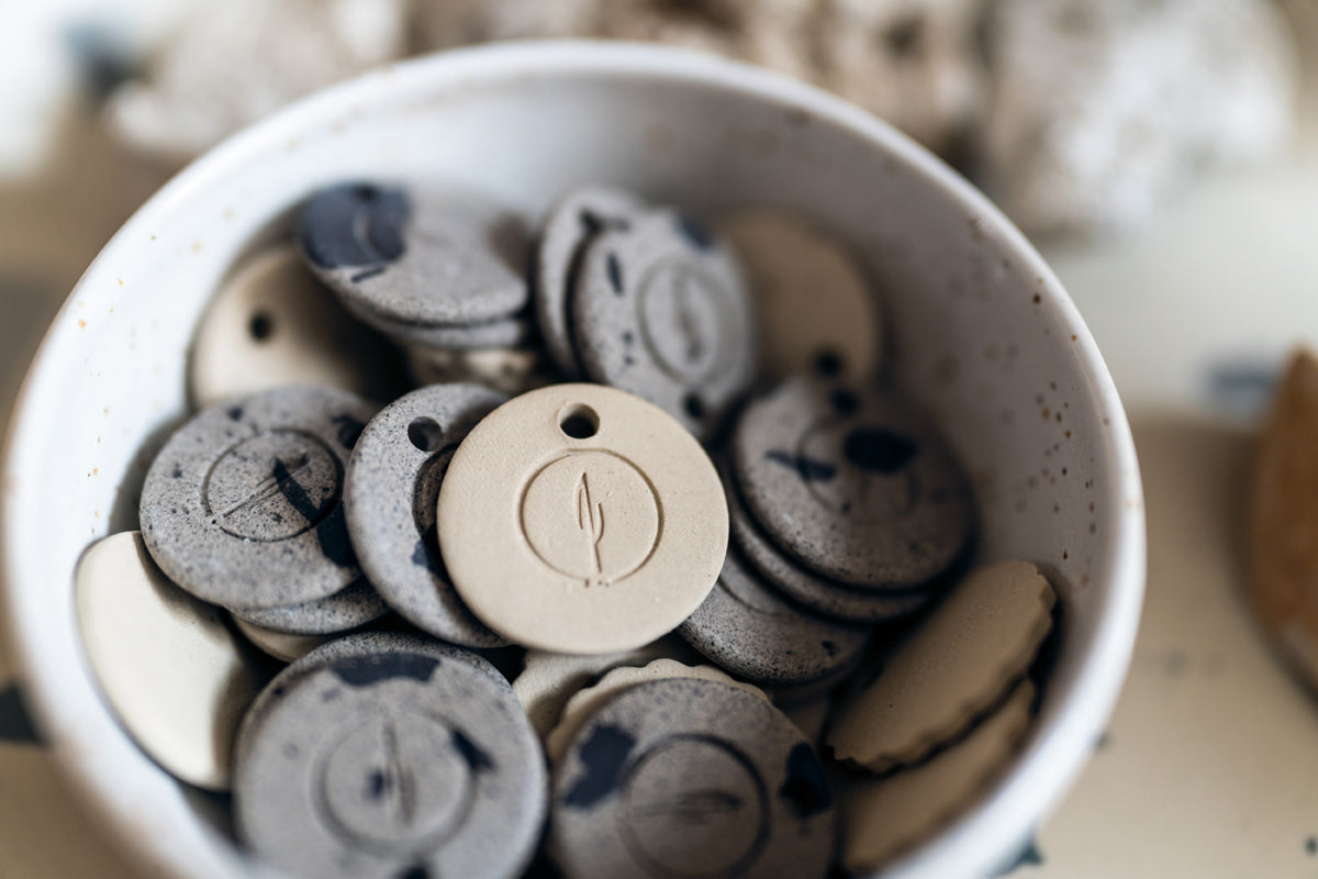 Embossed potter's mark pressed onto a circular clay disk.