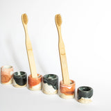 Arrangement of unique handmade toothbrush holders in coral red and blue, with two holders featuring wooden toothbrushes, creating a visually engaging linear composition.