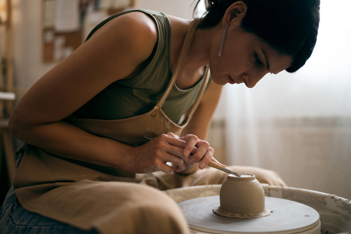 Jelena, the artisan behind Made of Dust Ceramics, meticulously trimming a cup on the potter's wheel.