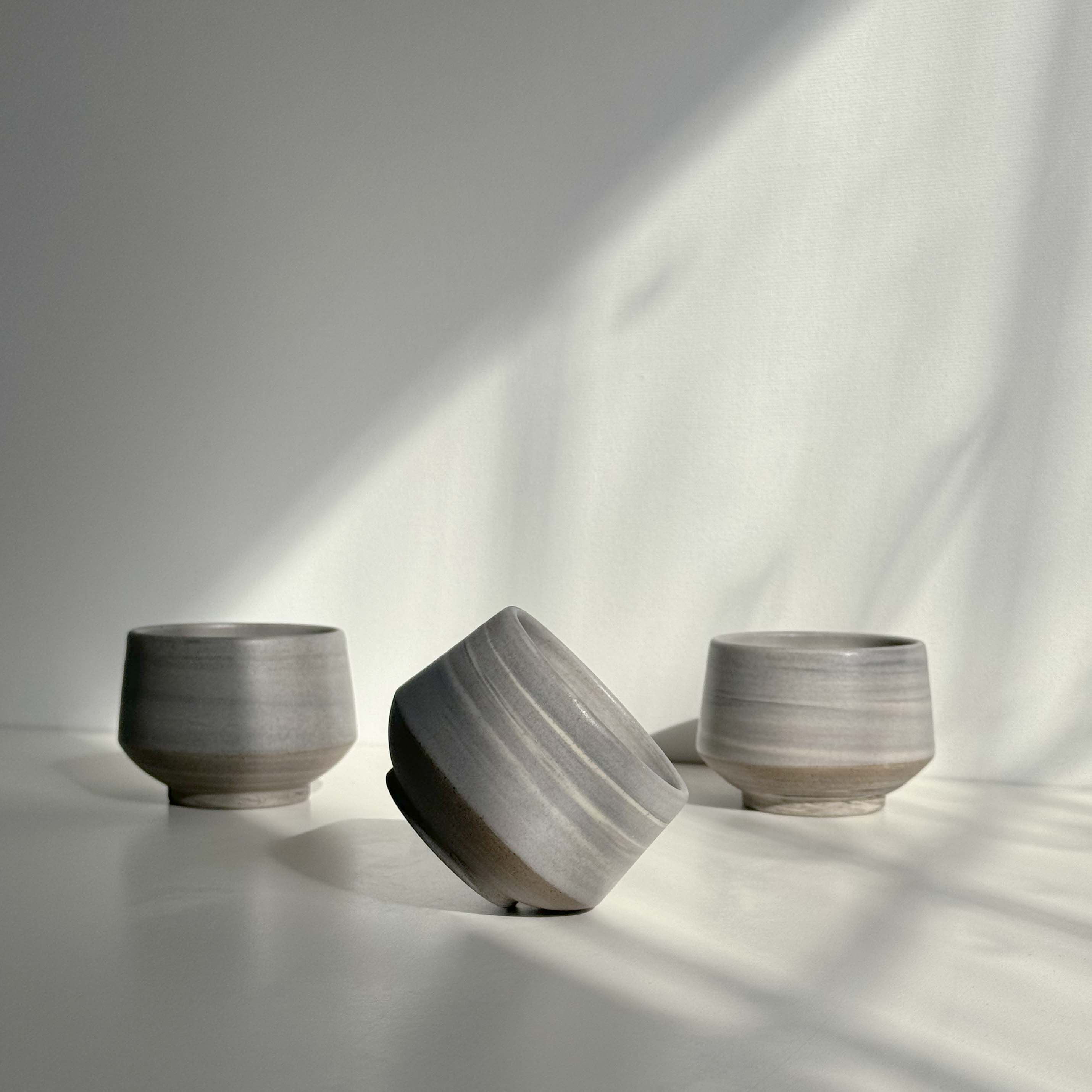 Handcrafted espresso ceramic cups scattered on a white surface.