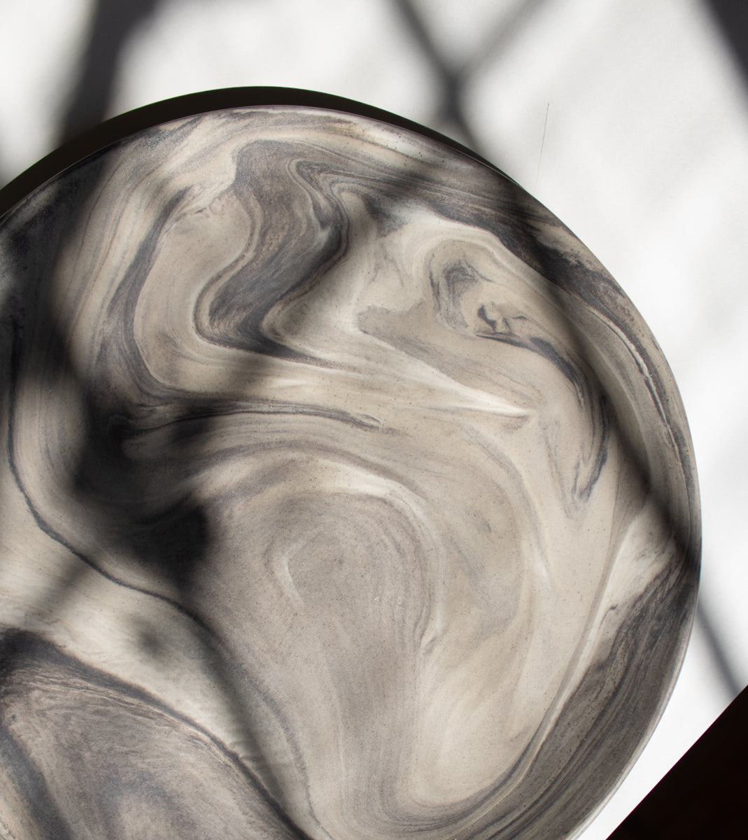 A handcrafted plate with a marble effect, illuminated by beautiful sunlight.