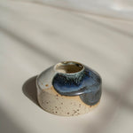 Close-up of a handcrafted miniature ceramic vase in midnight blue finish, photographed in natural daylight.