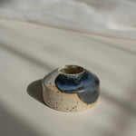 Close-up of a handcrafted miniature ceramic vase in midnight blue finish, photographed in natural daylight.