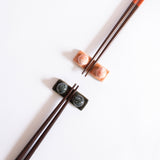 Handcrafted midnight blue and coral red chopstick rest with wooden chopsticks displayed on a white surface.