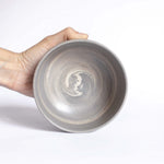 Close-up of a handmade ceramic bowl's interior in earthy, natural tones, held against a white backdrop