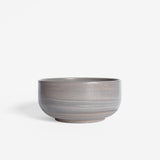 A handcrafted ceramic bowl in natural earthy tones set on a white background.