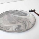 A handcrafted marbled ceramic plate and chopsticks arranged neatly on a white surface.