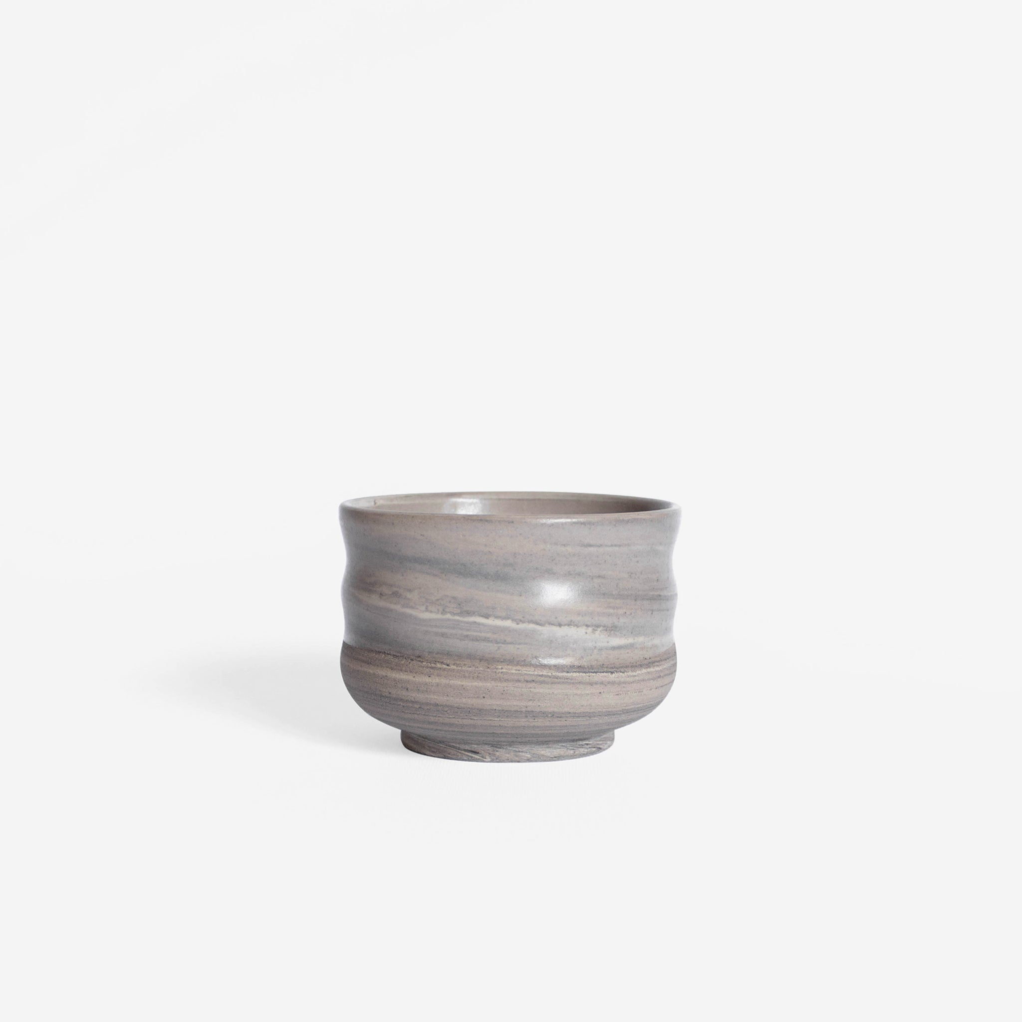 Handcrafted cappuccino cup with wavy walls, featuring a matte marble finish in natural earthy hues, set against a white background.