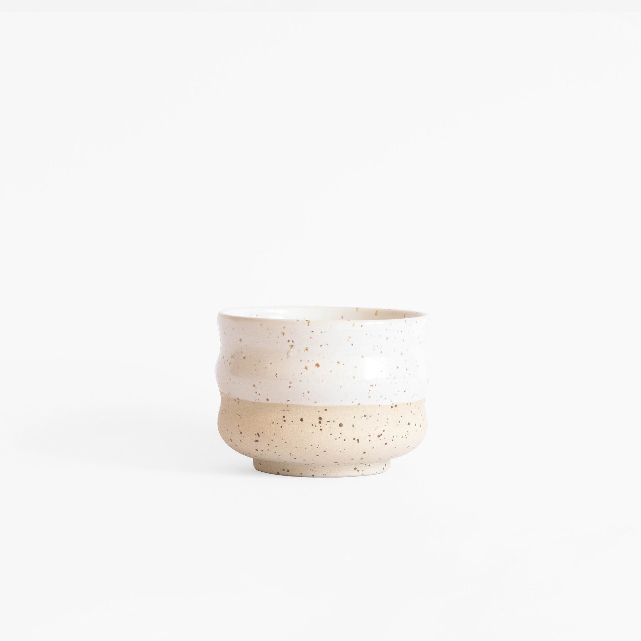 A handcrafted ceramic cappuccino cup in speckled white finish, set on a white background.