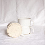 A group of three handmade ceramic cups with handles on a white background.