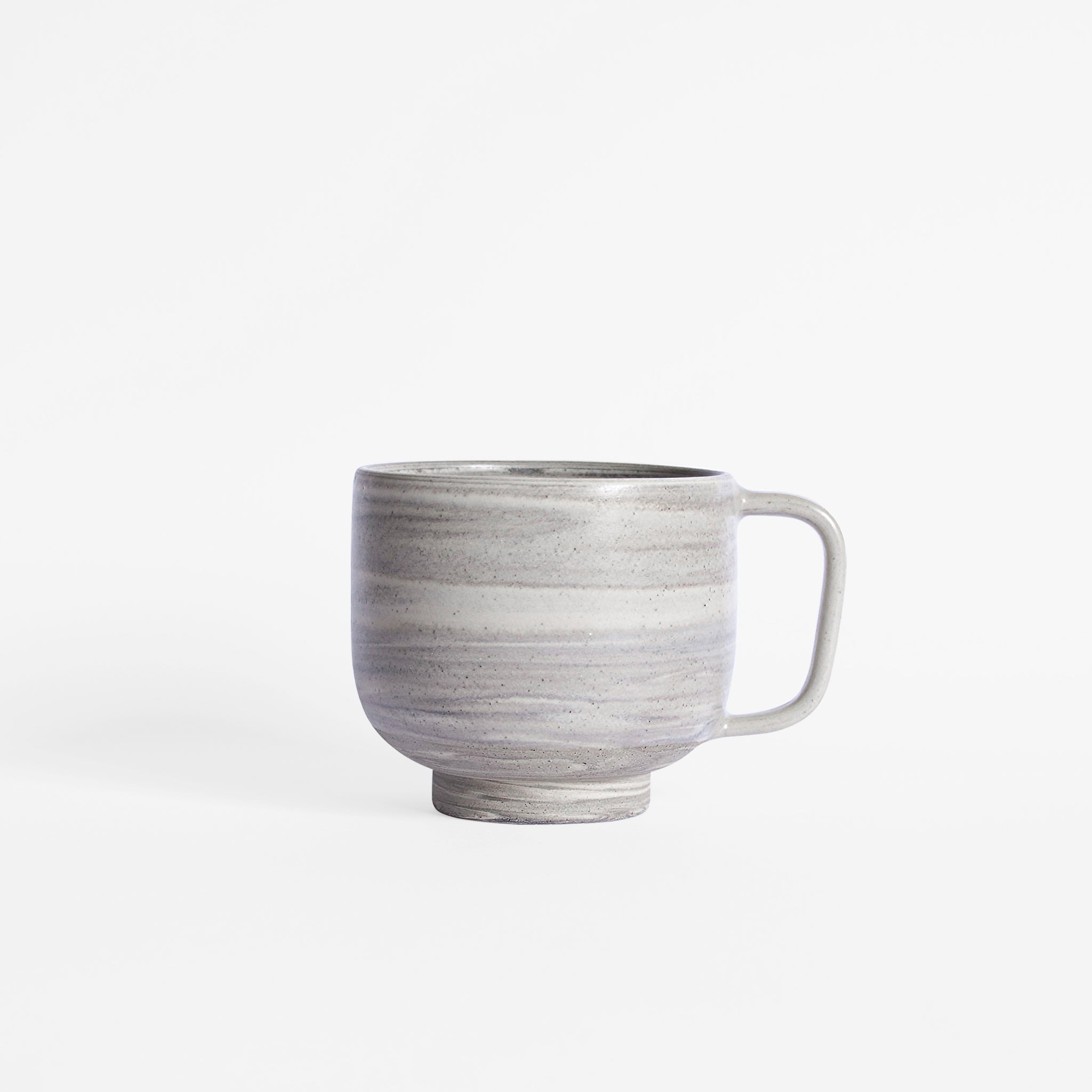 Handcrafted mug in earthy tones set against white surface.