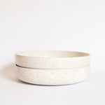 Two handcrafted ceramic pasta plates in speckled white finish, displayed on a white background.